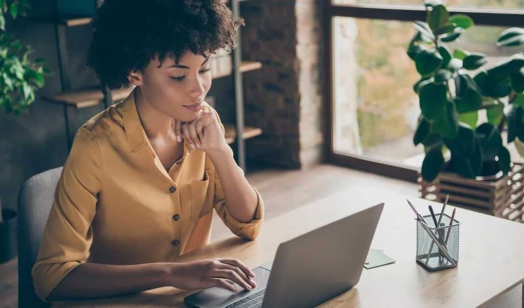 ERP Core Accounting Software to modernize manufacturing accounting. Woman sits at laptop in office.