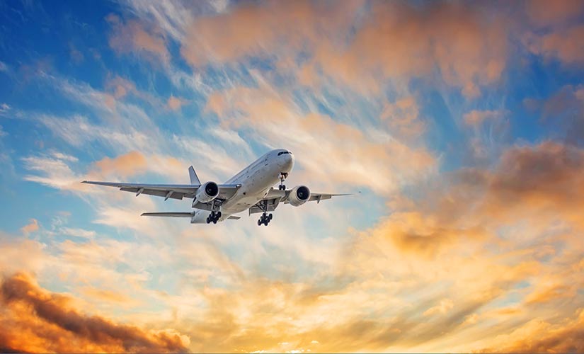 Airplane in setting-sun sky. QT9 QMS aerospace & defense compliance, AS9100 to IA9100.