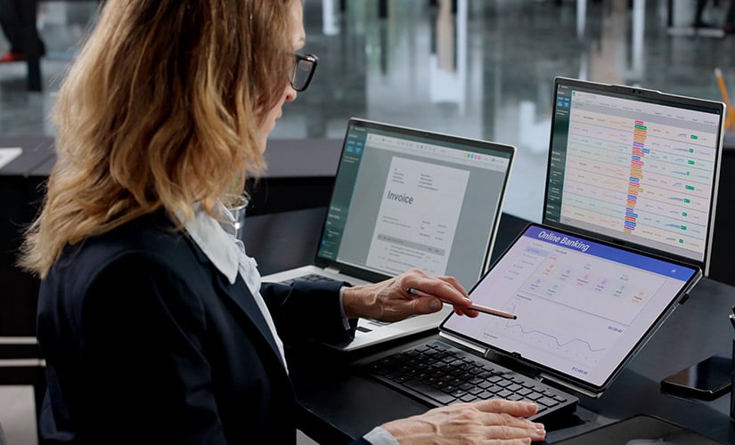 Woman using two laptops uses online banking software. QT9 ERP offers integration with Avalara tax software.