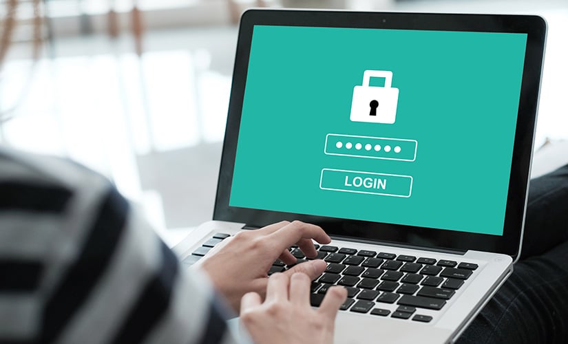 Hands on laptop keyboard with display of lock screen for article about cybersecurity and new department of defense cybersecurity maturity certification.