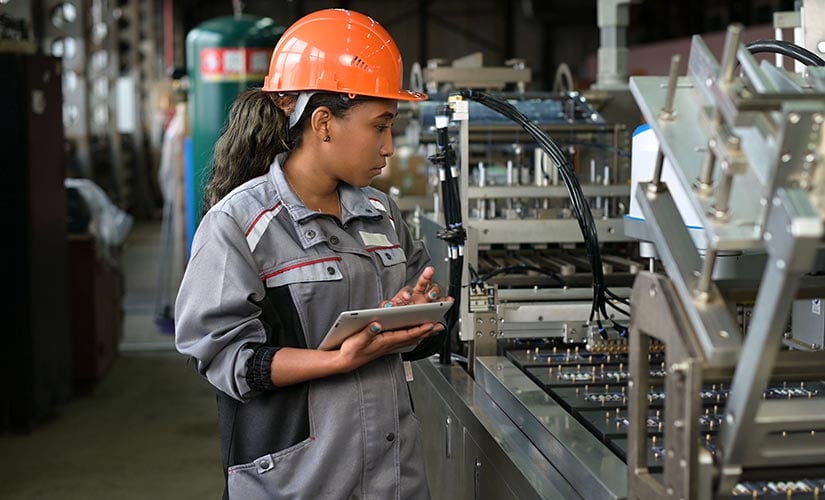 A woman uses a tablet for manufacturing in-process inspection with QT9 ERP software.