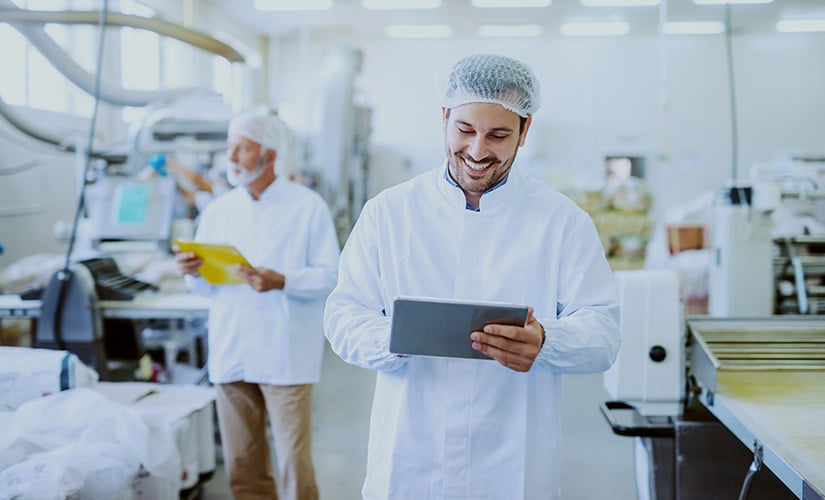 Man wearing lab coat and holding tablet in food processing facility preparing for new safe food quality standard edition 10.0