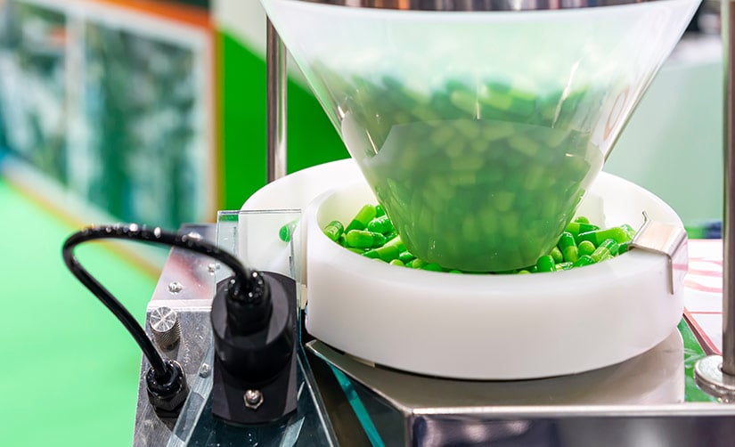 Electronic batch record systems help manage green capsules in plastic hopper for manufacturing automatic capsule filling machine. 