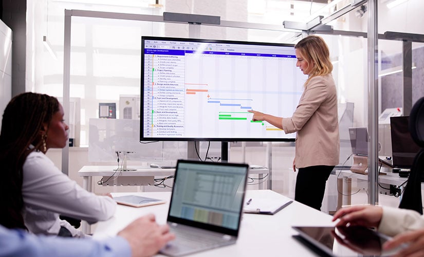 Woman stands at whiteboard demonstrating how to create a quality employee training class.