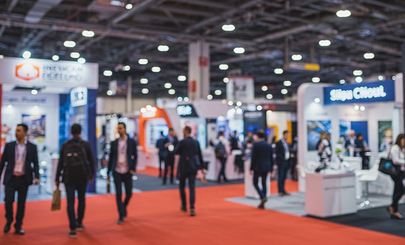 QT9 Software showcases its ERP and QMS platforms at the International Manufacturing Technology Show. Trade show floor with booths and people walking aisles. 